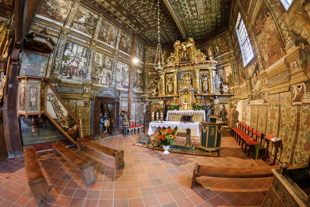 Zdobiony ołtarz główny i malowane ściany w drewnianym kościele w Binarowej