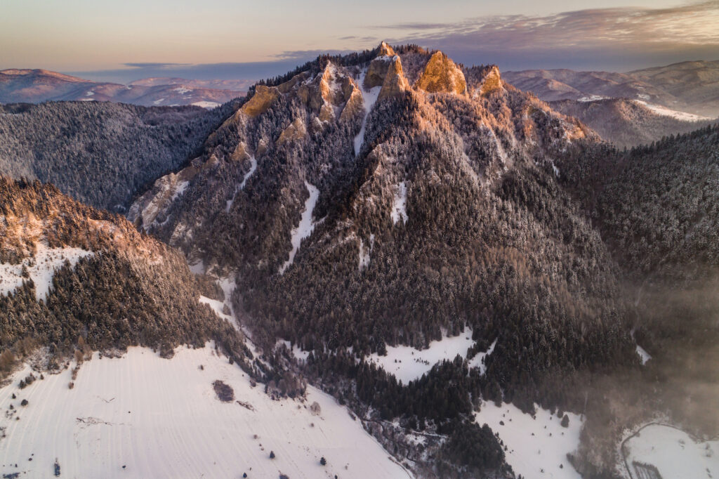 Trzy Korony zimą, pokryte śniegiem, oświetlone promieniami zachodzącego słońca