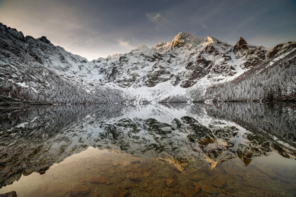 Zimowy widok na Morskie Oko z ośnieżonymi szczytami odbijającymi się w wodzie
