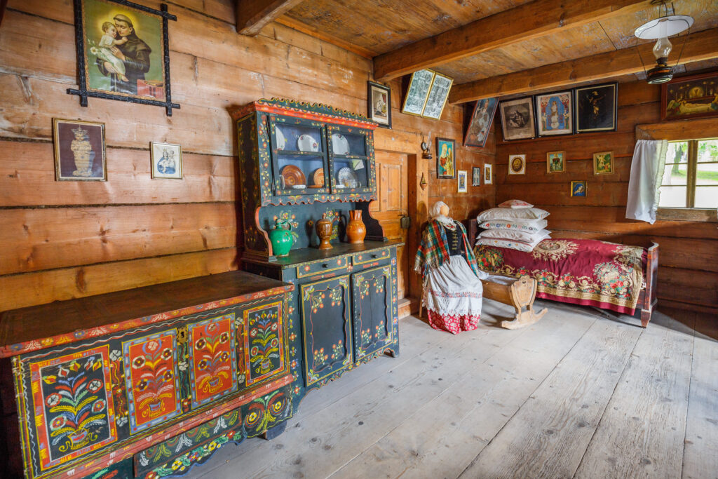 Tradycyjne wnętrze chaty chłopskiej z kolorowymi meblami i ludowymi dekoracjami w Wygiełzowie
