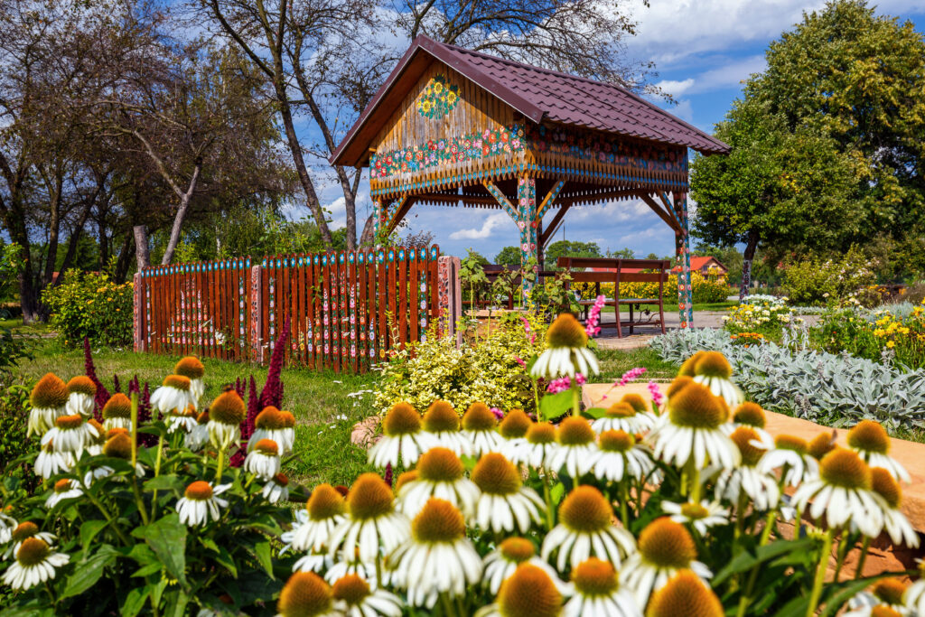 Altanka z kolorowymi ornamentami w ogrodzie pełnym kwiatów w Zalipiu