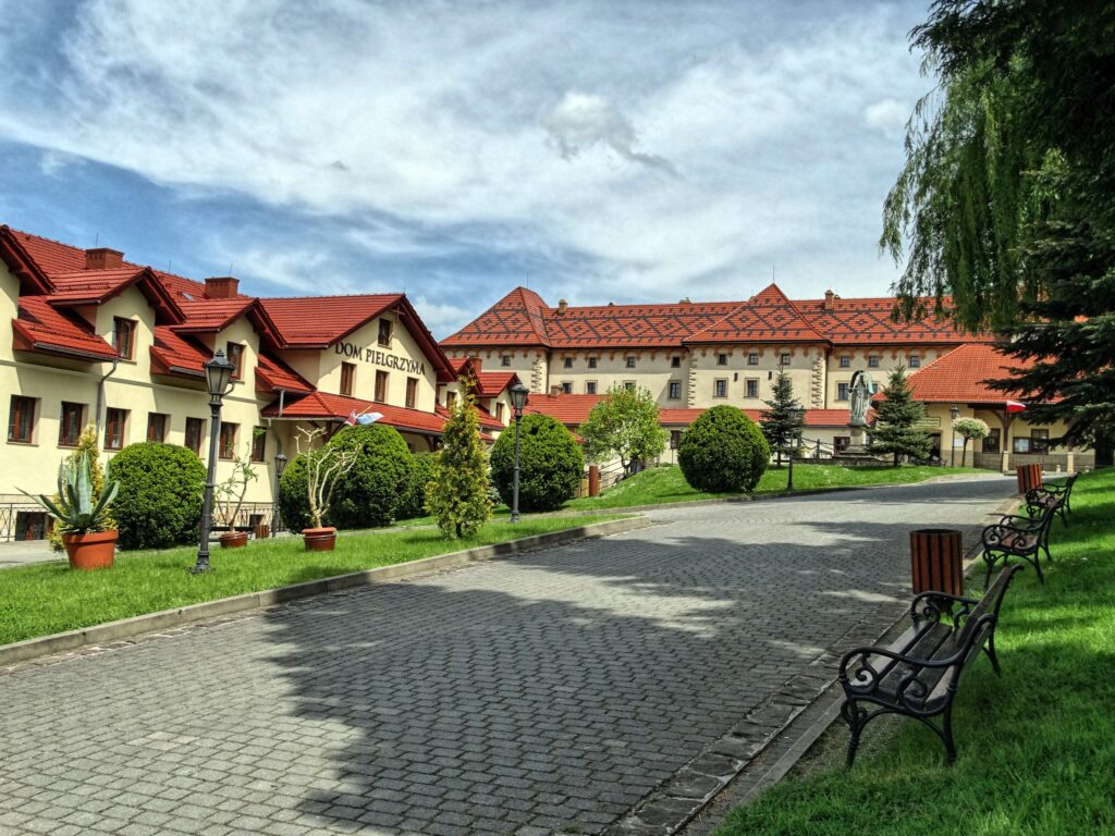 Dziedziniec klasztorny w Kalwarii Zebrzydowskiej z alejką i czerwonymi dachami budynków